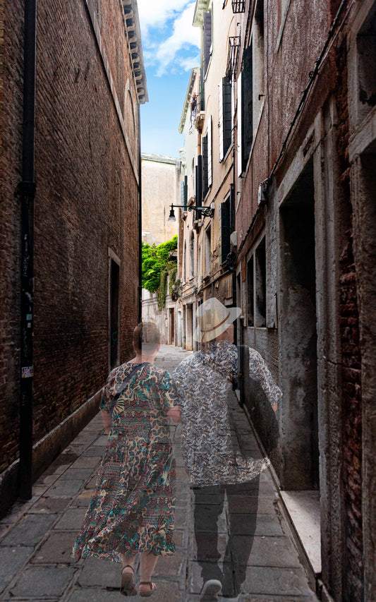 Two people walking down a narrow alleyway between old buildings.